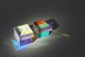 Two cubic glass prism refract light into different colors and cast shadows
