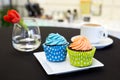 Two cup cakes in colourful paper cases on modern plate and cup o Royalty Free Stock Photo