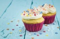 Two cup cakes with star sprinkles on blue table - background Royalty Free Stock Photo