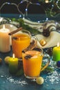 Two cup of hot spicy tea with sea buckthorn, cinnamon and star anise, branches of pine and spruce, candles and holiday decor,