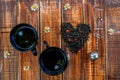 Two cup of tea near dry leaves black make in heart on wooden background Vintage strainer. concept. . Top view. Closeup. Love. Royalty Free Stock Photo