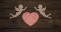 Two cupids and a heart made from wood texture background.