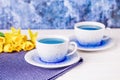 Two cups of blue tea and bouquet of daffodils, trendy blue butterfly tea