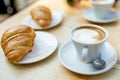 Two cups of capuccino coffee with croissants on a wooden table Royalty Free Stock Photo