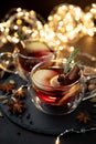 Two cups of Christmas mulled wine or gluhwein with spices and lemon slices on dark wooden background with defocused lights. Royalty Free Stock Photo