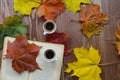 Two cups of coffee, a book and autumn leaves on a brown wooden table