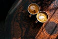 Two cups of coffee on brown vintage table with beautiful latte art. Flat lay view Royalty Free Stock Photo