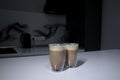 Two cups of coffee in double-botoom glass on white table in gray kitchen