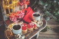 Two cups of coffee with ginger cookies in the form of red mittens on a Christmas chair next to the Christmas tree