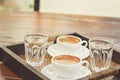 Two cups of coffee placed on a wooden tray selective focus.