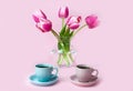 A two cups of coffee and a vase with pink tulips on the pink background. Copy space. Close-up Royalty Free Stock Photo