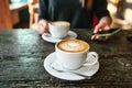 Two cups of coffee on a wooden table, a young girl holding a phone in her hand and going to call. Waiting for a meeting Royalty Free Stock Photo