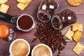 Two cups of espresso, crackers, cookies, holder with ground coffee, tamper and cans of coffee beans on wooden table Royalty Free Stock Photo