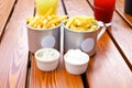 Two cups of french fries and two creamy sauces, lemonades on brown boards wooden table. Fastfood, potato. Front view, mockup