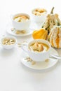 Two cups with fresh pumpkin cream soup decorated cream, seeds and crackers