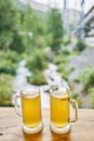 Two cups of ginger root tea with lemon, honey and mint on a wooden table and High-mountain river in the background. Walk Royalty Free Stock Photo