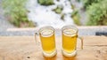 Two cups of ginger root tea with lemon, honey and mint on a wooden table and High-mountain river in the background. Walk Royalty Free Stock Photo