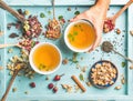 Two cups of healthy herbal tea with mint, cinnamon, dried rose and camomile flowers in different spoons, woman's hand Royalty Free Stock Photo