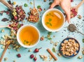 Two cups of healthy herbal tea with mint, cinnamon, dried rose and camomile flowers in different spoons, woman's hand Royalty Free Stock Photo