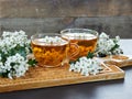 Two cups of herbal haw thorn tea from flower buds around blooming branches on wooden cutting board Royalty Free Stock Photo