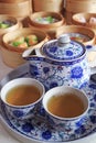 Two Cups of Hot Chinese Oolong Tea with Assorted Dim Sum Dishes in Background