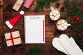 Two cups of hot cocoa or chocolate with marshmallow, gifts, mittens, christmas fir tree and notebook with to do list. Flat lay.