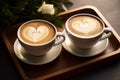 Two cups of hot coffee cafe latte with beautiful heart shaped latte art and white rose, served on wooden table, coffee lover and