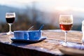 Two cups of hot coffee and two glass of red wine are on the old wooden table which is outdoor among of sunlight in the morning for Royalty Free Stock Photo