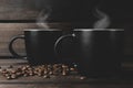 Two cups of hot coffee with steam and coffee beans on a wooden and black background. hot drink Royalty Free Stock Photo