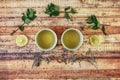 Two cups of hot drink for support own immunity. Curious herbals on wooden board. Nettle, lemon and mint leaves. Typical asian tea