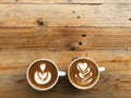 Two cups of hot latte coffee with two different latte art, put on natural brown wood table Royalty Free Stock Photo