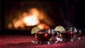 Two cups with hot tea on a table with a red tablecloth, in the background a fire burns in the fireplace Royalty Free Stock Photo