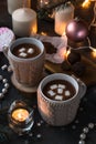 Two cups in knitted mittens of fresh hot cocoa or chocolate on wooden christmas background, dark photo Royalty Free Stock Photo