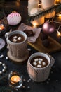 Two cups in knitted mittens of fresh hot cocoa or chocolate on wooden christmas background, dark photo Royalty Free Stock Photo