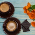 Two cups and saucers filled with hot coffee stand on a blue wooden table.