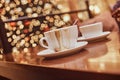 Two cups with spilled coffee on the wooden table in a coffee shop, blur background with bokeh effect Royalty Free Stock Photo