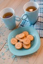 Two cups of tea on a blue napkin. Biscuits on a blue plate on a wooden background Royalty Free Stock Photo