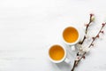 Two cups of tea and branches of blossoming apricot on a white rustic table with empty space for text or image. Top view