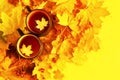 Two cups of tea decorated with a maple leaf and autumn bright yellow-red foliage on a yellow background, top view Royalty Free Stock Photo