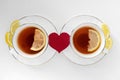 Two cups of tea with lemon and red heart on white background. The concept of relationship, happy couple in love