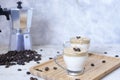 Two cups of whipped coffee on a bamboo tray with a blurred coffee machine with coffee beans sprinkled on a white background.