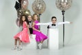 two curly-haired girls and two boys engaged in ballroom dancing, laughing and mischievously posing in a photo studio