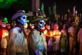 Two costumed cowboys with skull make-up in front of a line of costumed people with candles and graveyard at the event for dias de