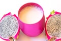 Two cut dragon fruit halves on either side of a pink cup of milk on white background Royalty Free Stock Photo