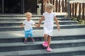 Two cute adorable caucasian blond little siblings walking down stiars residential building. Reliable elder sister Royalty Free Stock Photo