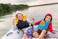 Two cute adorable little caucasian sibling boy and girl wearing lifejacket vest having fun enjoy riding inflatable Royalty Free Stock Photo