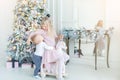 Two cute adorable little siblings brother and sister having fun playing with retro wooden wheel horse toy near christmas tree in Royalty Free Stock Photo