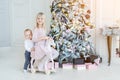 Two cute adorable little siblings brother and sister having fun playing with retro wooden wheel horse toy near christmas tree in Royalty Free Stock Photo