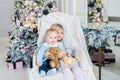 Two cute adorable little siblings brother and sister sitting in chair near christmas tree in cozy living room looking , dreaming Royalty Free Stock Photo