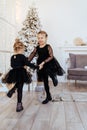 Two cute adorable little sisters near christmas tree in cozy living room. Royalty Free Stock Photo